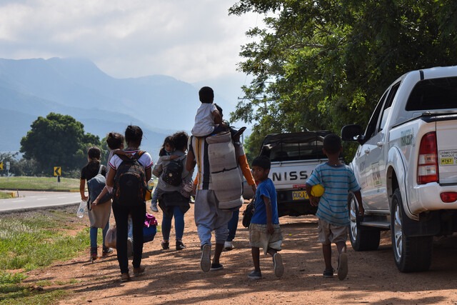 Migrantes venezolanos caminan con maleta al hombro intentando pasar la frontera. 